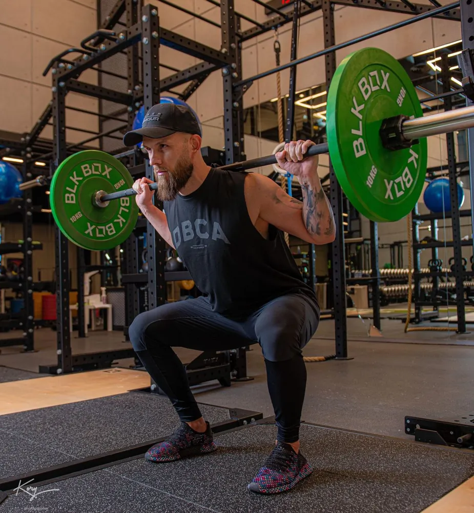 Barbell back squat with green weight plates