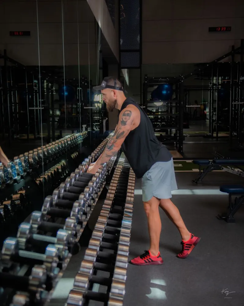 Trainer walking along a dumbbell rack