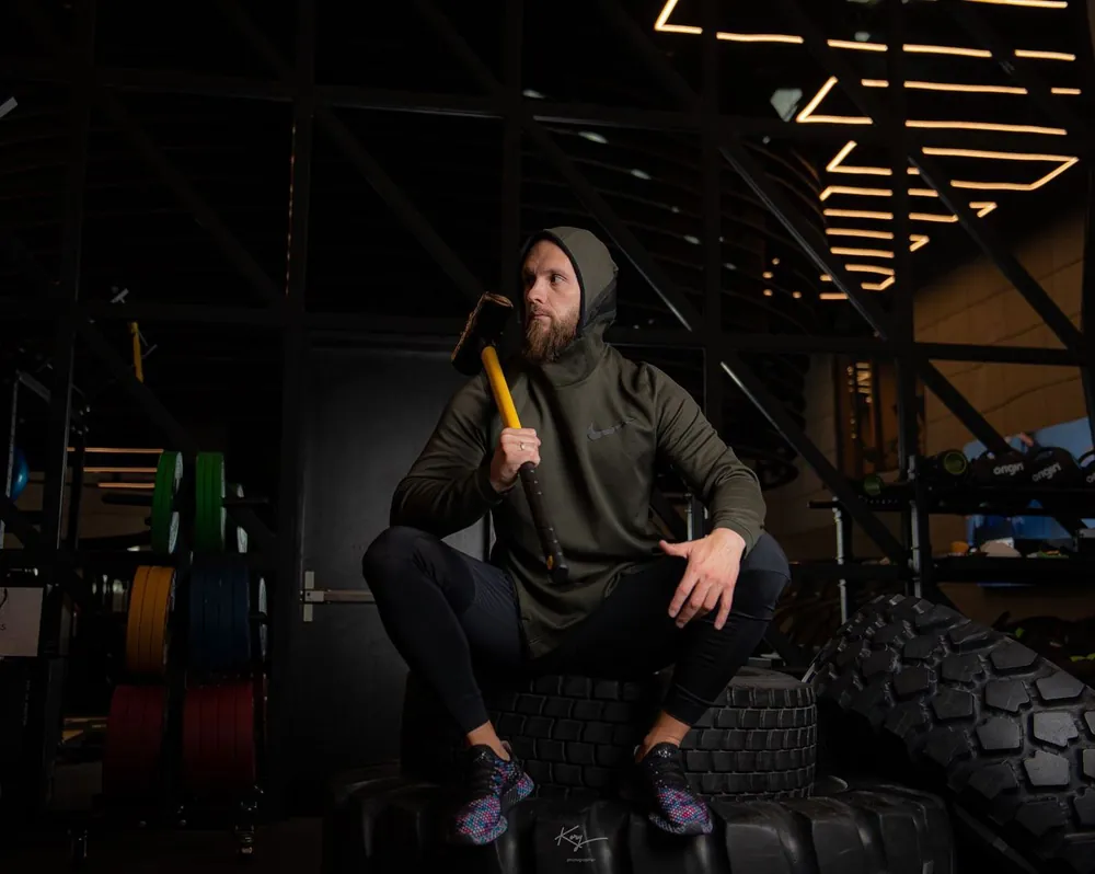 Trainer resting on tires holding a sledgehammer
